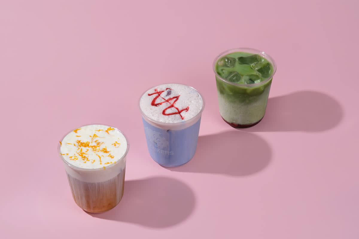 Three iced drinks lined up on a pink backdrop