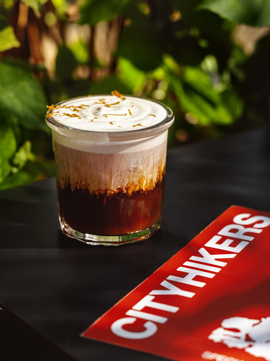An iced coffee under a cap of citrus cold foam